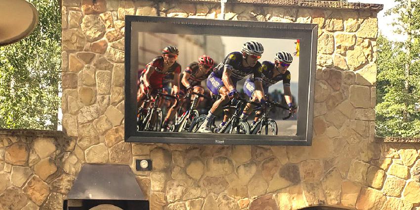 A stone structure with a mounted outdoor TV cabinet visible, with cycling on screen