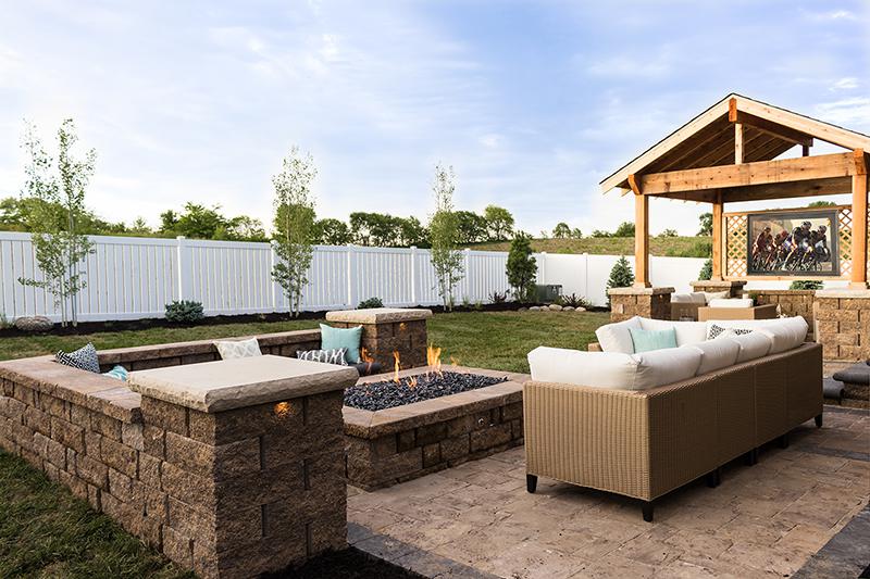 A garden with a fire pit, with a TV under cover and cycling on the TV 