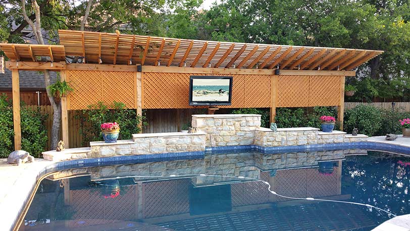 A pool area with an outdoor TV, mounted directly in front of the pool