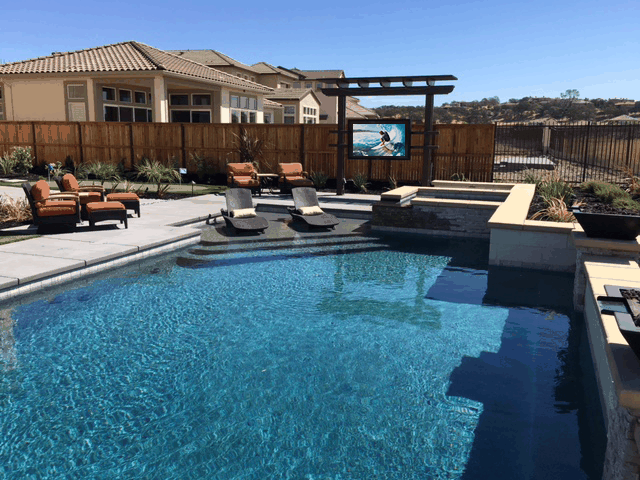 Geometric pool with pool seating combined with modern trellis featuring TV in The TV Shield PRO outdoor TV enclosure