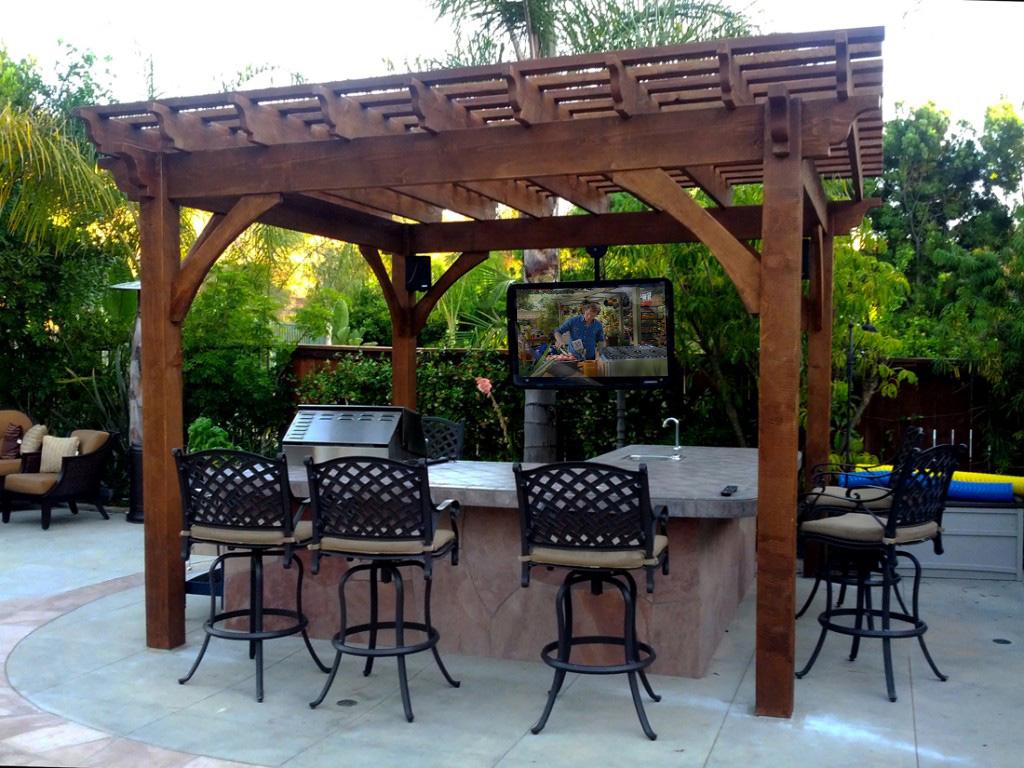 Outdoor kitchen, bar, and pergola combo with sleek The TV Shield outdoor TV enclosure 