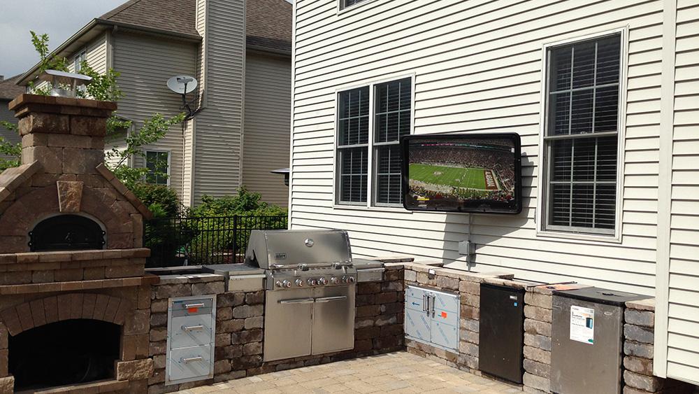 Wall mounted outdoor TV solution paired with kitchen and fireplace 